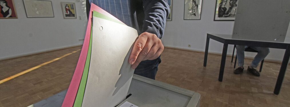Eine Person wirft Wahl-Unterlagen in einen Kasten